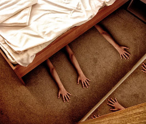 Cropped hands of people below bed