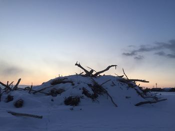 Silhouette of snow on landscape against sky during sunset