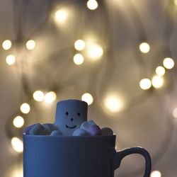 Close-up of coffee cup on table with christmas lights in background