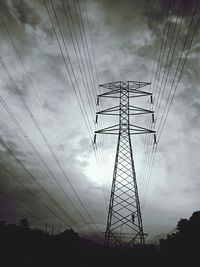 Low angle view of electricity pylon against cloudy sky