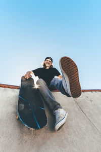 Happy man with skateboard sitting at skateboard park