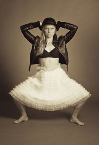 Portrait of mid adult woman crouching against gray background