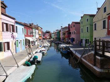 Boats moored in canal amidst buildings in city