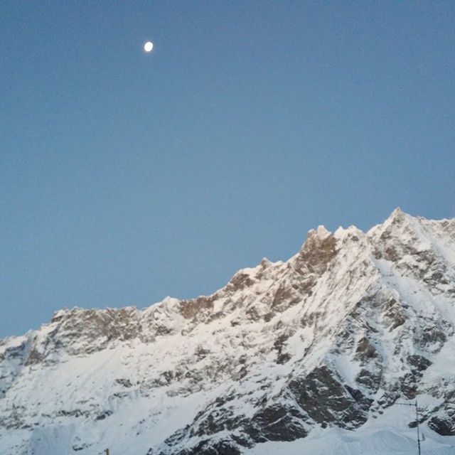 clear sky, copy space, blue, low angle view, tranquility, moon, tranquil scene, scenics, mountain, snow, beauty in nature, nature, winter, cold temperature, rock - object, outdoors, idyllic, landscape, non-urban scene, sky