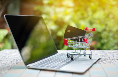 Small shopping cart and laptop on table outdoors