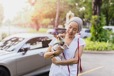 Side view of young woman drinking water from car