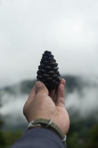 Close-up of hand holding ice cream against sky