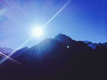 Sun shining through clouds over mountains