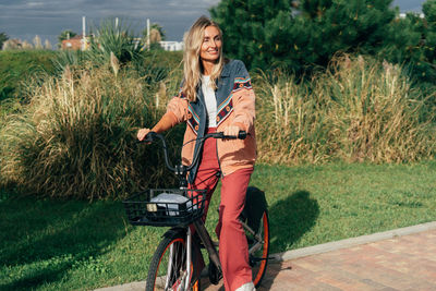 Young happy woman rides a rented electric bike.