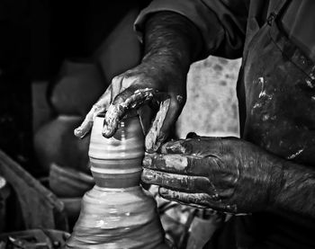 Midsection of person making clay pot in workshop