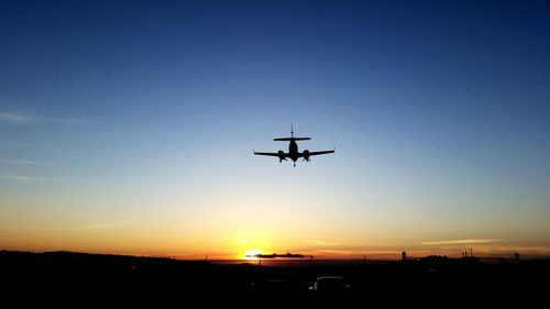 Airplane flying in sky at sunset