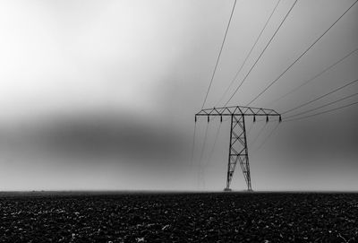 Electricity pylon on field against clear sky