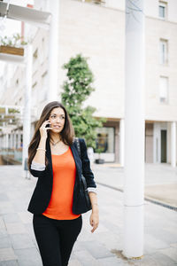 Young woman talking on phone outside building