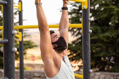 Athletic male exercising chin-ups in playground