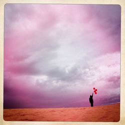 Full length of man standing on bench against cloudy sky