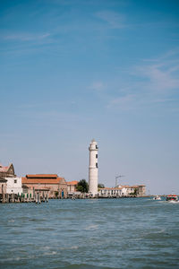 Lighthouse by sea against sky