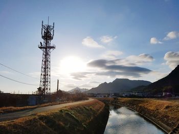 Electricity pylon by mountain against sky