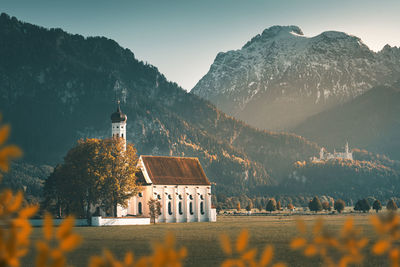 Built structure by trees and buildings against sky