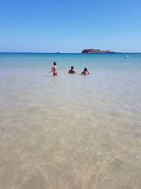 People on beach against clear sky