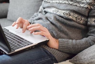 Midsection of man using laptop on sofa at home