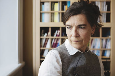 Close-up of thoughtful female lawyer against bookshelf in library