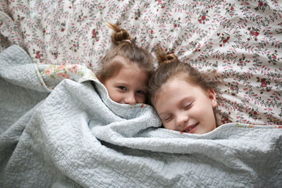 Sister's girls play and cuddle under a blanket, emotions. concept childhood