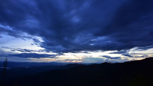 Scenic view of silhouette mountains against dramatic sky