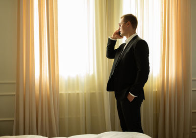 Modern adult businessman calling by phone in hotel