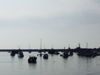 Boats moored at harbor against sky