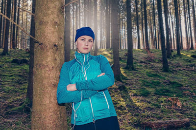 Portrait of young woman standing against trees