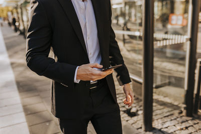 Mid section of businessman using cell phone