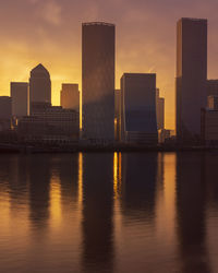 Modern buildings in city against sky during sunset