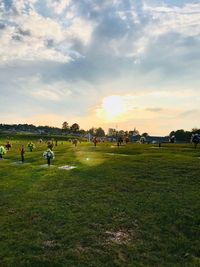 People on field against sky during sunset