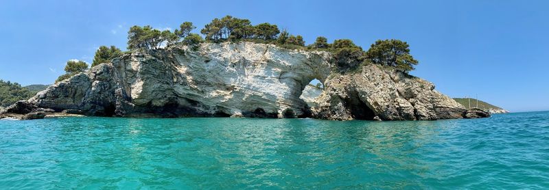 Rock formation in sea against blue sky