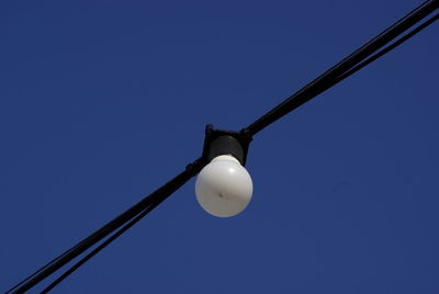 Low angle view of light bulb against blue sky