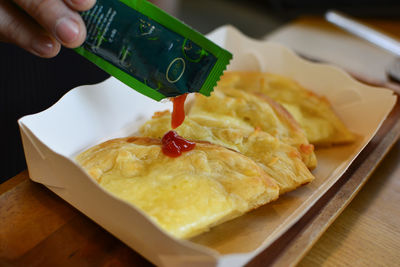 Cropped hand of person preparing food on table