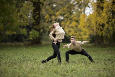 Young couple dancing on grassy field at park