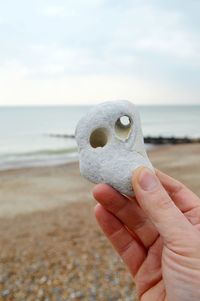 Cropped hand of person holding rock at beach