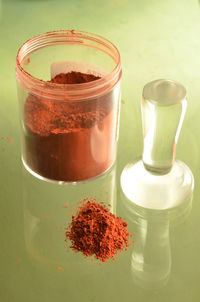 High angle view of ground red chili pepper on glass table