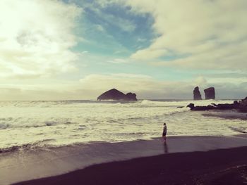 Man standing at beach against sky