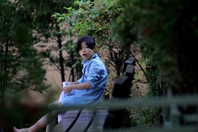 Side view portrait of shocked girl sitting on bench at park