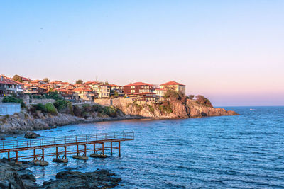 Houses by sea against clear blue sky