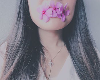 Midsection of woman with pink periwinkles in mouth wall