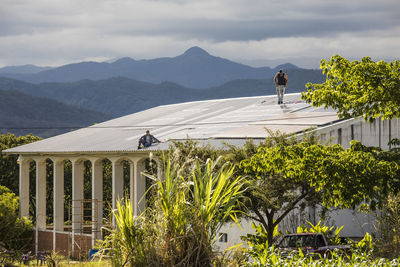 Two electricians work to install solar panels on roof.