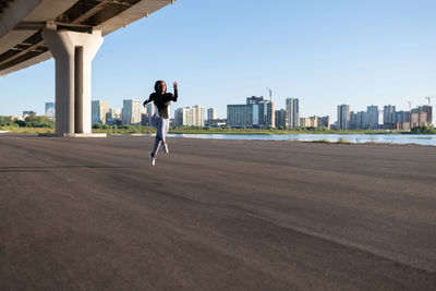 Black runner leaping under bridge