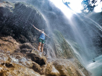 Man standing on rock formation in water