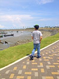 Rear view of man standing on riverbank against sky