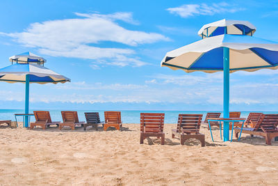 Deck chairs on beach against sky