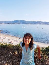 Portrait of beautiful woman standing by sea against sky