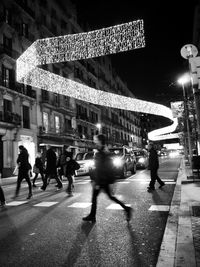 Woman standing on illuminated city street at night